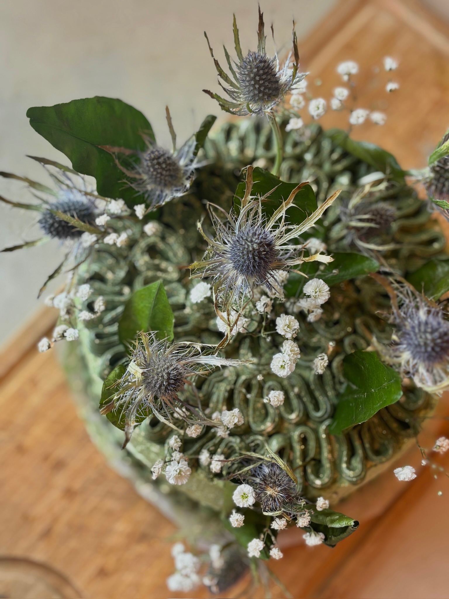 Sage green thistle cake with baby's breath, top view